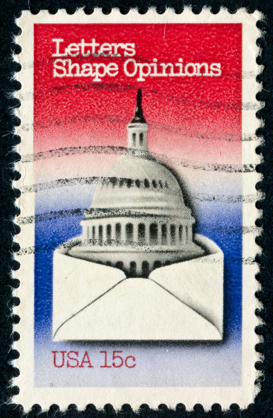 Postage stamp with the U.S. Capitol building emerging from an envelope, background in red, white, and blue gradient. Text reads: "Letters Shape Opinions" and "USA 15c".