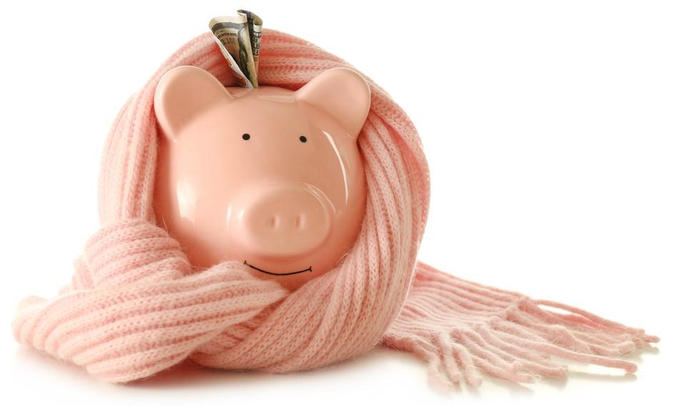 Pink piggy bank wrapped in a pink knitted scarf against a white background.