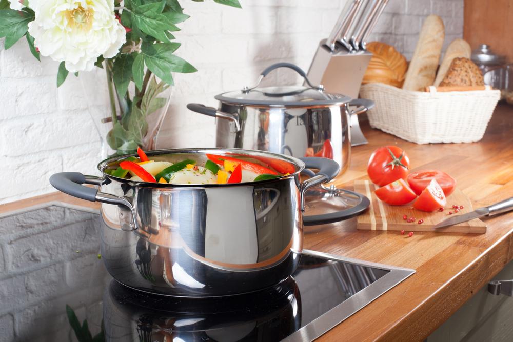 Kitchen with pots on the stovetop, a cutting board with tomatoes, and a basket of bread.