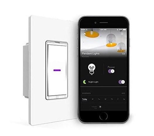 a modern electronic light switch alongside a smartphone displaying a lighting control application. Positioned to the right, the smartphone screen shows various controls and a dashboard for managing "Pendant Lights". Below that, there's a section with a light bulb icon labeled "Power" with an on/off toggle control next to it, and a moon icon labeled "Night Light" with another toggle control. The lower section features a scheduling panel with days of the week and a timeline.